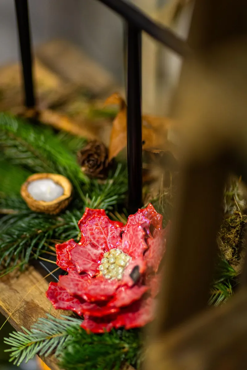 Czerwony ceramiczny hibiskus wśród świerkowych gałązek